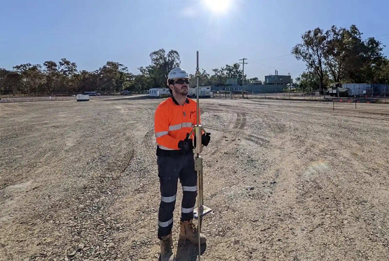 Man using a dynamic cone penetrometer to test soil on construction site